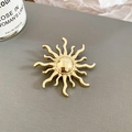 Nahaufnahme der goldenen Sonnenbrosche mit polierten Metallstrahlen auf Texturhintergrund - Sonnenstrahlungsform (3#) / Gold
