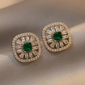 Vista macro di orecchini vintage dorati con pietre verde smeraldo e piccoli cristalli - Perno d'Argento - Orecchini Geometrici Verdi