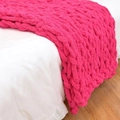 Handmade chunky knit chenille blanket in vibrant rose red draped over a white bed - 25*100cm / Rose Red