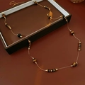 Détail d'un collier vintage avec perles oeil de tigre marron et chaîne métal sur fond rétro - café