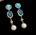 Orecchini a goccia blu con cristalli e pendenti di perle su sfondo nero - Orecchini a Bottone con Nappine di Perle Ovali Blu (Perno in Argento 925)