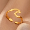 Close-up of golden wave-shaped adjustable stainless steel ring on champagne silk - Gold Wave (C1435)