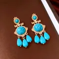 Dettaglio di orecchini vintage dorati con pietra turchese e pendenti a goccia - Oro-Blu