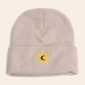 Close-up of the sun and moon embroidery on a beige thick knitted beanie hat - Khaki