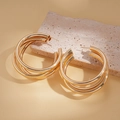 Detail van gelaagde gouden ronde oorringen op een beige stenen ondergrond - Goud Meerlaagse Grote Ring (925 Sterling Zilveren Oorbelpost)