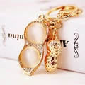Goldener Erdnuss-Schlüsselanhänger mit beige Opalen und Strasssteinen auf Geschenkbox - Erdnuss-Anhänger mit Katzenaugenstein / Gold