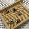 Faceted dalmatian jasper oval pendants with gold bail connectors on a bamboo tray - Dalmatian Jasper