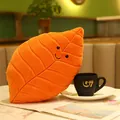 Plüschkissen in orangefarbener Blattform mit lachendem Gesicht neben einer Tasse - 25*38cm / Oranges Blatt