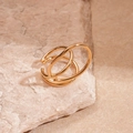 Detailed macro view of triple-layered golden ear cuff resting on a textured natural stone - Gold