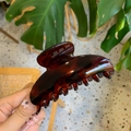 Detail of dark tortoiseshell hair claw clip held in hand with resin texture and glossy finish - 10cm Yuanbao Claw / Glossy Red Brown