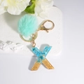 Blue resin letter X keychain with gold flakes and light green faux fur pompom - Letter X