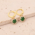 Detailed view of gold heart earrings with green zircon centers on a stone plate - Green Earrings