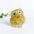 Yellow natural crystal resin owl ornament with detailed texture on white background - Agate