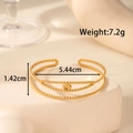 Minimalistische gouden drielaagse kralenarmband op een witte stenen displaystandaard - Drielaagse Kraal