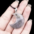 Natural labradorite crescent moon pendant with black cord held in hand for scale - 30mm Labradorite