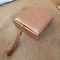 Dettaglio di una scatola per gioielli quadrata oro rosa con trama a onde e nappa - Piuma d'Oro - Scatola per Bracciale