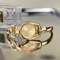 Macro detail of golden horseshoe-shaped bangle watch with elegant Roman numerals - Gold Case Gold Dial