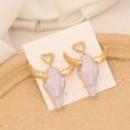 Detail of bohemian bull skull earrings with gold hearts on a white display card - White