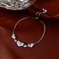 Detail van verstelbare zilveren armband met zirkoon hart en strik op rode zijde - Zilver