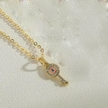 Makro-Detail des goldenen Schlüsselanhängers mit Evil Eye Design und Zirkonia-Steinen - Rosa Schlüssel