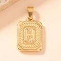 Macro detail of a vintage gold-plated square pendant with embossed letter H and textured finish - Letter H