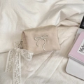 Flat lay of small off-white canvas cosmetic bag with bow embroidery and lace detail - Beige with Lace