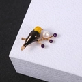 Macro detail of a colorful bird brooch with white pearl on a golden branch - Bird
