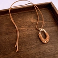 Détail d'un pendentif goutte vintage sur cordon en daim marron avec enroulement doré - Café Or-Goutte
