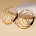 Detail of layered gold geometric twist earrings with dark wrapped wire on a stone base - Gold