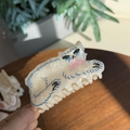 Détail d'une pince à cheveux chat en acétate nacré blanc avec un nœud rose et des accents bleus - Chat Persan aux Yeux Verts