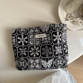 Detalle de bordado floral vintage en un neceser de lona negra con etiqueta decorativa - Bordado de Mariposa y Copo de Nieve en Fondo Negro