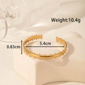 Adjustable golden stainless steel open bangle with gear edges on stone pedestal - Gear Edge Geometric