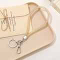 Detail showing a sparkly gold silicone key ring with silver clasp on a beige tray - Champagne