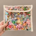 Hand holding transparent PVC bag filled with colorful cartoon children hair accessories - Main Image Packaging 200 Pieces