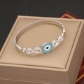 Detailed macro of silver titanium steel bangle with blue evil eye and infinity symbol charms - Infinity Symbol Evil Eye Style (7#)
