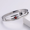 Detail of silver bangle featuring black and red star charms with rows of white zircons - Steel