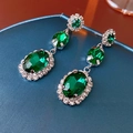 Vue macro de boucles d'oreilles ovales vert émeraude avec cristaux sur velours bleu - Boucles d'Oreilles Tige en Argent - Vert