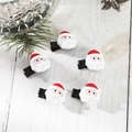 Dettaglio di cinque fermagli per capelli a forma di Babbo Natale su fondo di legno bianco - Set di 5 Fermagli per Capelli Testa di Babbo Natale
