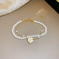 Detalle de una elegante pulsera de perlas de doble hilera con colgante de camelia dorada - Pulsera de Perlas de Doble Fila de Camelia Dorada