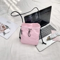 Pink drawstring mini crossbody phone bag on a white textured bed with lifestyle accessories - Pink