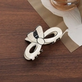 Elegant beige bow hair claw clip with black trim on a rustic dark wood surface - Bow Claw Clip / Beige
