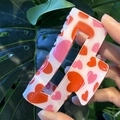 Macro shot of square hair claw clip with red and pink heart patterns on a green leaf - White with Pink & Red Hearts