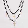 Primer plano de collar de doble capa con cuentas negras facetadas y cruces doradas - Collar