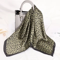 Close-up of olive green leopard print satin scarf draped elegantly on a grey handbag - Green