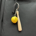 Mini yellow softball and wooden bat keychain hanging on a black canvas bag - Yellow