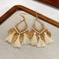 Bohemian gold leaf earrings with beige cotton tassels on a rustic display tray - Round Gold Hollow Leaf Tassel Style