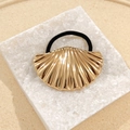Golden scallop shell hair tie with elastic band on a white stone display stand - Shell Hair Tie
