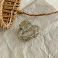 Detailed macro view of the marble pattern resin hair claw clip on aesthetic beige paper - Blue Yellow Iridescent