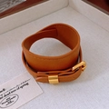 Detail of vintage brown faux leather cuff bracelet with gold metal buckle on display - Brown
