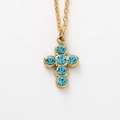 Dettaglio di una collana a croce dorata con sei cristalli blu tondi su una sottile catena a maglie - Blu Lago